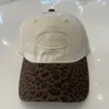Detailopname van stijlvolle honkbalpet met beige kroon, luipaardprint rand en borduurwerk. - Verstelbaar / Luipaard Kleurblok Beige