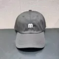 Detailopname van een donkergrijze baseballpet met een witte geborduurde letter m aan de voorkant. - Verstelbaar / Zwart