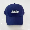 Close-up van een donkerblauwe honkbalpet met witte Sunday-borduursel, casual stijl. - Verstelbaar / Marineblauw