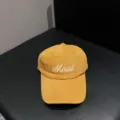 Detail view of a mustard yellow cotton brushed baseball cap with white embroidered Mood text. - Adjustable / Caramel color