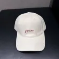 Gedetailleerde close-up van een mooie gebroken witte katoenen honkbalpet met rode tekst. - Verstelbaar / Beige