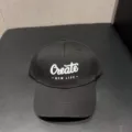 Detailopname van een zwarte baseballpet met witte geborduurde Create tekst en brede rand. - Verstelbaar / Zwart