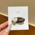 Detailansicht der braunen Glitzer Haarspange mit süßem gepunkteten Herz und eleganten Buchstaben. - Beige Herz