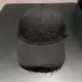 Detailopname van de zwarte streetwear honkbalpet met borduurmerk en gerafelde rand. - Zwart