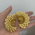 Vue en gros plan détaillée des boucles d'oreilles pendantes en or au design rétro et texturé. - Style Plume Superposée (3511) / Or