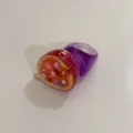 Gros plan sur la bague en résine fruit de figue fantaisie avec strass et bracelet violet. - Figue