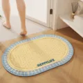 Detailed view of oval woven bathroom floor mat with blue and white border for home use. - Cream Yellow with Blue Edge