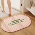 Oval pink white striped bath mat with green embroidered text detail in a cozy home bathroom - Pink Stripes