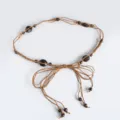 Bohemian style braided waist rope detail showing delicate wooden beads and cord knotting. - Camel