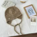 Elegante braune gesprenkelte Strickmütze mit Ohrenklappen und geflochtenen Bändern winterlich. - Einheitsgröße / Khaki