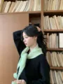 Dettaglio della sciarpa triangolare in maglia verde con ponpon, morbido accessorio invernale. - Verde