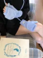 Detail view of light blue knitted convertible fingerless gloves with string and cute label. - One Size / Blue