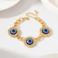 Bracelet breloque mauvais œil doré avec strass scintillants, design à triple cercle élégant. - Oeil du Mal Doré