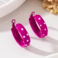 Gros plan de boucles d'oreilles créoles en métal fuchsia avec pois blancs élégants. - Rose rouge