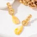 Gros plan détaillé de disques en or martelé élégants avec des boucles d'oreilles en résine jaune. - Style Goutte d'Eau en Résine Jaune (JMX-ER9829-B)