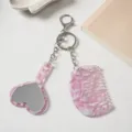 Detailed view of the pink marble acetate heart mirror and comb keychain pendant accessory. - Pink