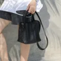 Λεπτομέρεια μαύρης πλεγμένης δερμάτινης τσάντας bucket, casual χιαστί τσάντα μόδας. - Μαύρο