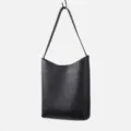 Black leather shoulder bag hanging detail, minimalist daily hobo bag design, premium texture. - Black