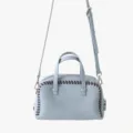 Gros plan detail du sac a main boston en cuir bleu clair avec bordure surpiquee marron et sangle. - Bleu