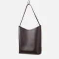 Dark brown leather shoulder bag detail, minimalist underarm bag hanging display view. - Coffee