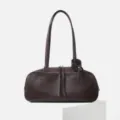 Dark brown top-layer cowhide bowling shoulder bag, close-up of zipper and knot handle detail. - Ebony
