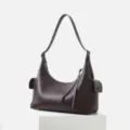 Dark brown leather shoulder bag detail, featuring side pockets and smooth zipper closure. - Ebony