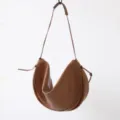 Détail de sac porté épaule croissant en cuir marron, design drapé unique, accessorio élégant. - Marron