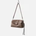 Brown leather shoulder bag detail showing soft cowhide texture, metal clasp and braid. - Coffee