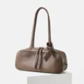 Detailed view of brown genuine leather bowling shoulder bag with zipper and long handle. - Coffee