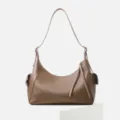 Detailed shot of the brown leather shoulder bag showing texture and side pocket design. - Coffee