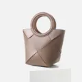 Detailed view of the stylish woven leather handbag with geometric design and round handle. - Caramel color