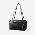 Close-up view of the black crocodile embossed cowhide underarm handbag showing texture. - Black
