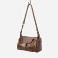 Brown leather shoulder crossbody pillow bag with metal buckle detail and adjustable strap. - Dark Apricot