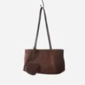 Close-up detail view of dark brown suede hobo shoulder bag featuring attached mini pouch. - Coffee