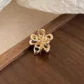 Gros plan détaillé d'une mini pince à cheveux fleur en métal doré, accessoire élégant. - Or