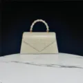 Elegant rhinestone pearl evening bag detail, sparkling crystal clutch handle closeup view. - Gold