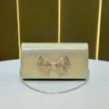 Borsetta da sera lucida color oro champagne con fiocco in strass e tracolla a catena d'argento - Oro