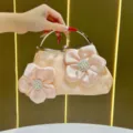 Elegante borsa da sera in raso rosa con design floreale di perle e manico ad anello dorato. - Rosa