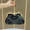 Elegante borsa da sera nera con struttura in metallo dorato, manico ad anello e decoro floreale. - Nero