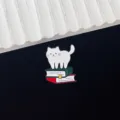 Detailed close-up shot of the cute cat enamel pin standing on books, perfect metal badge. - White Cat Standing on Books Style (R214)