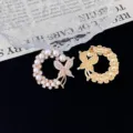 Close-up detail of the exquisite pearl and rhinestone butterfly wreath brooch clasp. - Butterfly Wreath Style (R311) / Gold