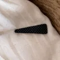 Detailaufnahme einer schwarzen Stoff-Haarspange mit weißen Punkten auf hellem Leinen. - Schwarzer Dreieck-Stil