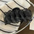 Primo piano di una molletta per capelli nera in rete con strass scintillanti, vista dettaglio. - Nero