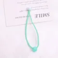 Vista dettagliata di un grazioso elastico per capelli verde con perla, ideale per bambini. - 1 Pezzo/Confezione / Ciano