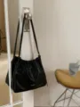 Detailed view of black pleated cloud shoulder bag lifestyle display hanging on door handle. - Black