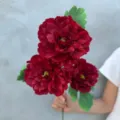 Detailansicht eines dunkelroten künstlichen Blumenstraußes mit grünen Blättern für Dekorationen. - Luoyi Pfingstrose