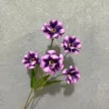 Primo piano dettagliato di teste di fiori di ranuncolo viola artificiali con foglie verdi casa. - Viola