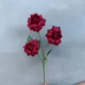 Detailaufnahme von künstlichen roten Rosen mit drei Blüten und grünen Blättern für Dekor. - 3-Kopf Feenrose