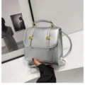 Silver mini backpack detail view, featuring metallic buckles, top handle and sleek texture. - 20x9x20cm / Silver