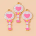 Close-up detail shot of cute magical wand enamel charms with pink heart and gold trim. - Pink